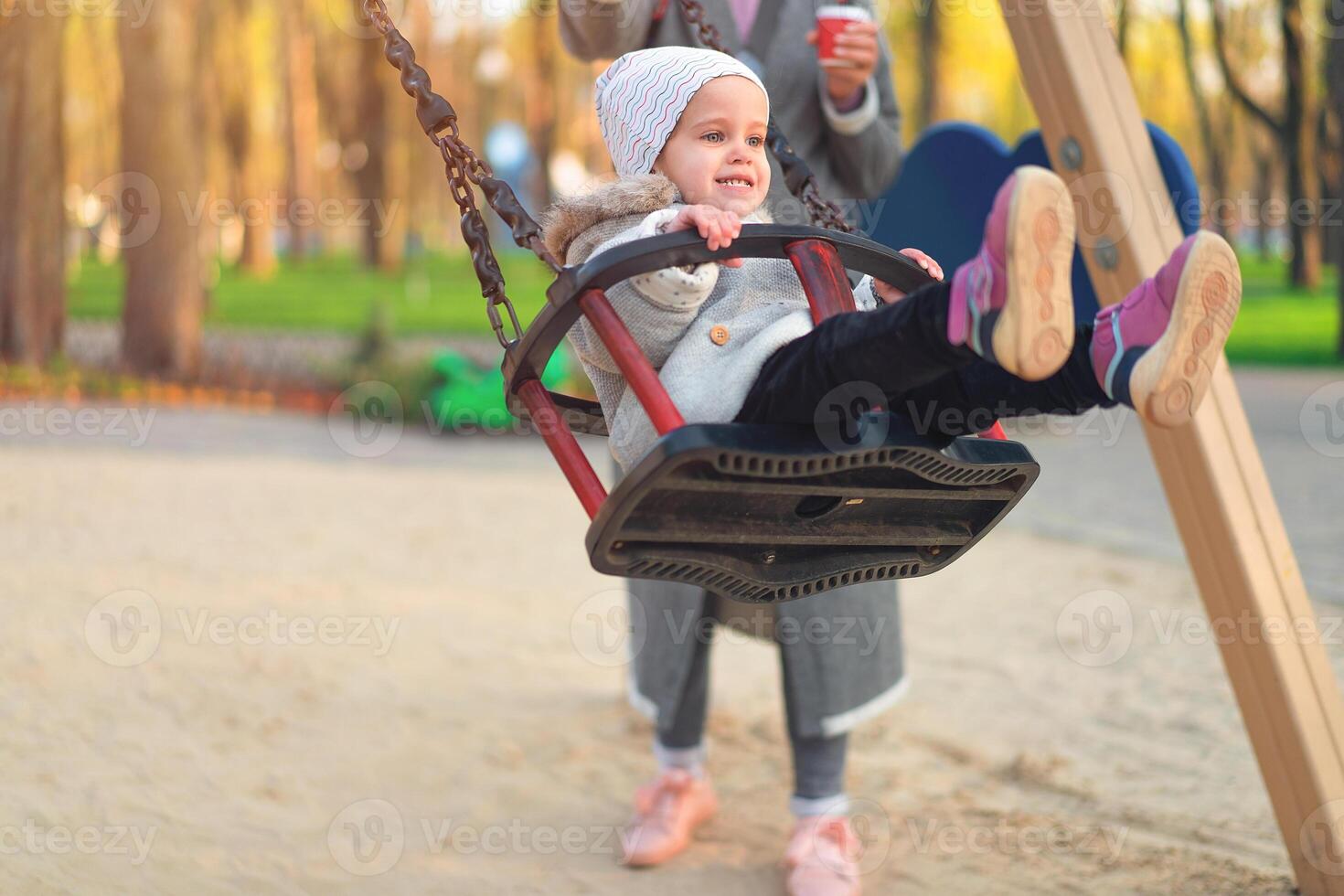 Happy child girl on swing in sunset fall. Little kid playing in the autumn on the nature park photo