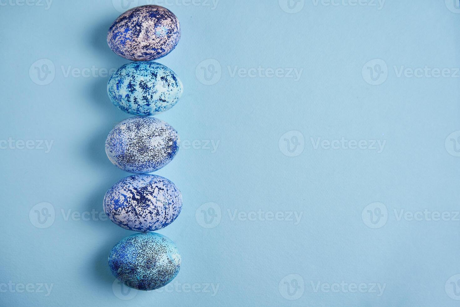 Beautiful blue easter eggs lie in a row on a blue paper background. photo