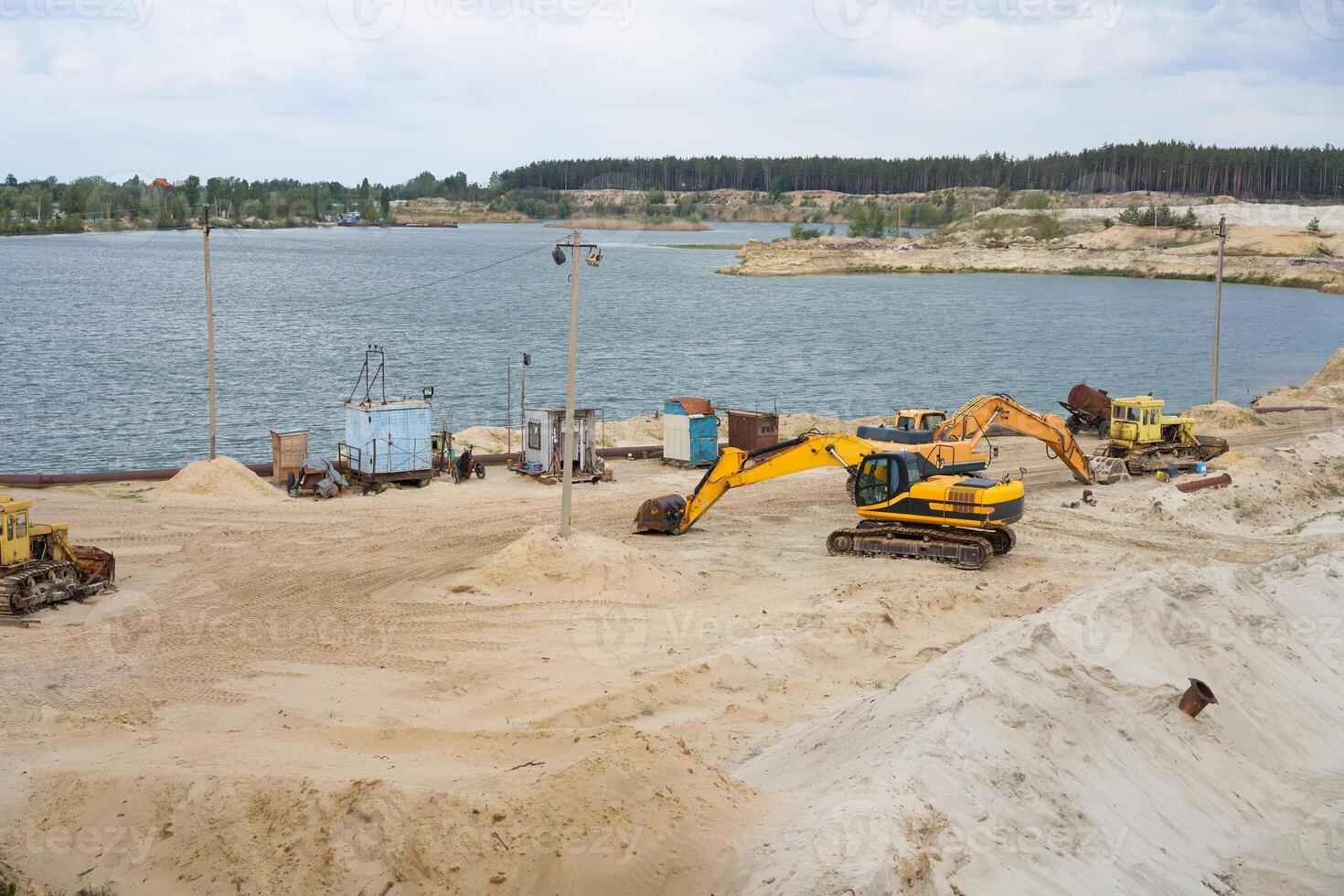 Sand quarry mining industry equipment excavator tractor standing sand land near lake water photo