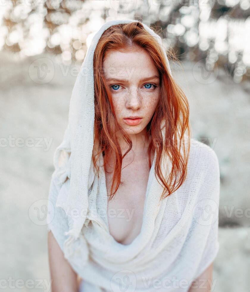 Close up portrait of a beautiful red haired girl in white medieval dress on glowing sun. Fairy tale story about brave heart woman. photo