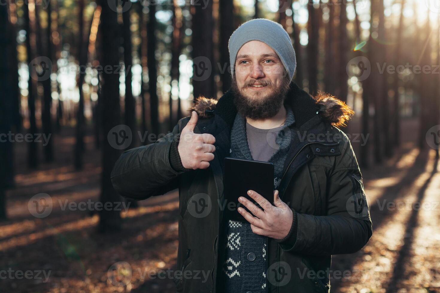 Portrait of adult man walking in the pine forest with digital tablet. photo