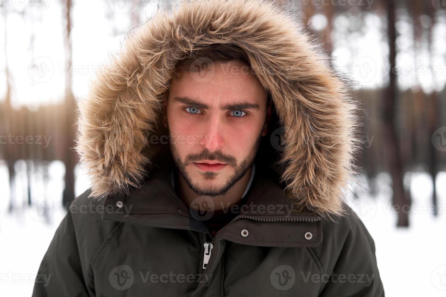 Attractive bearded man standing outdoors in winter season forest. photo
