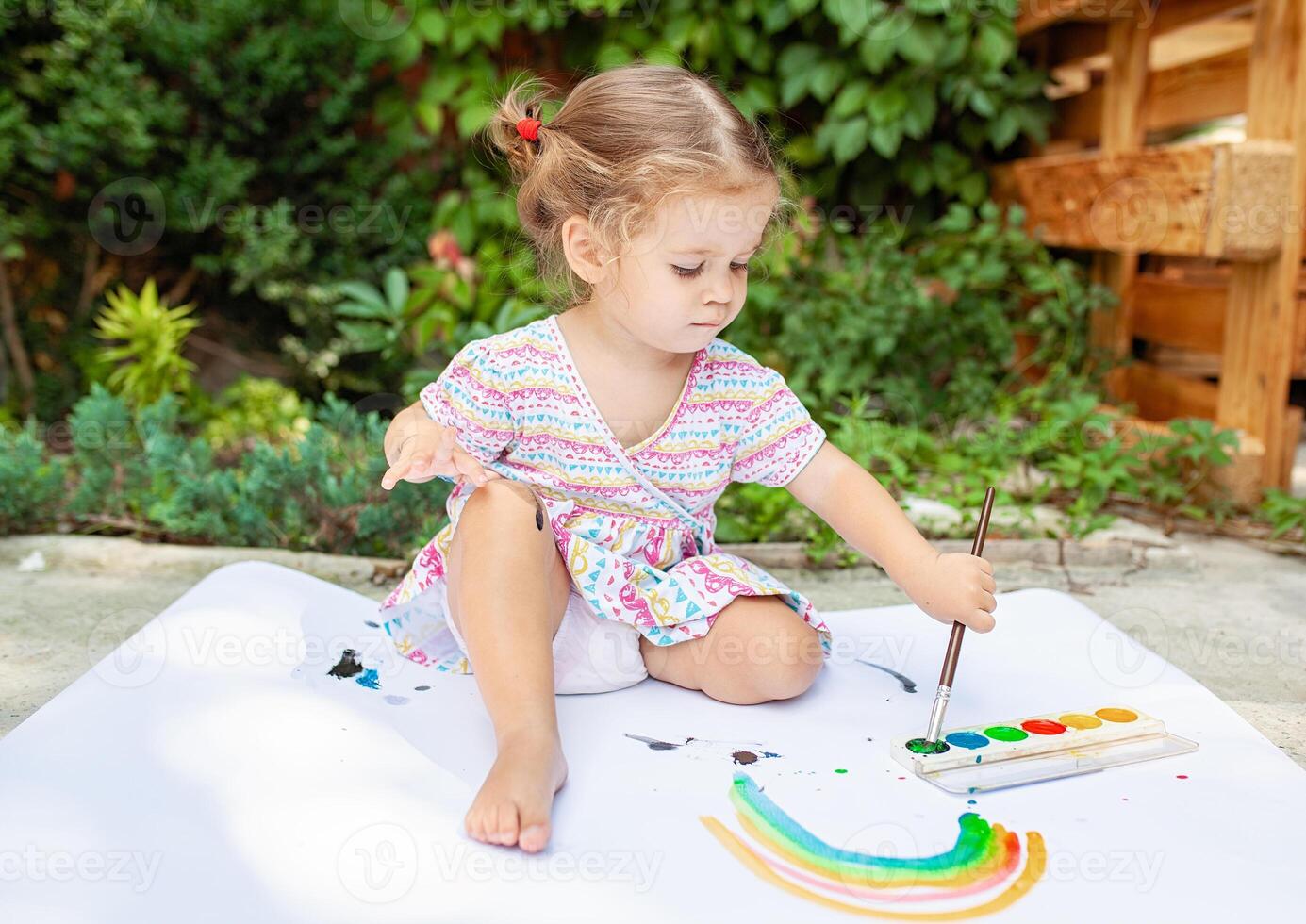 Cute little caucasian Girl enjoying Painting at the backyard with paper, water colour and art brush. Selective focus photo