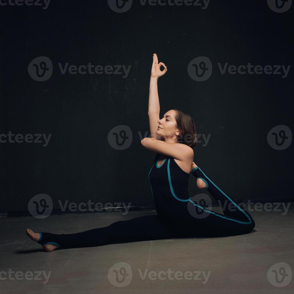 Woman practicing yoga against a dark texturized wall photo