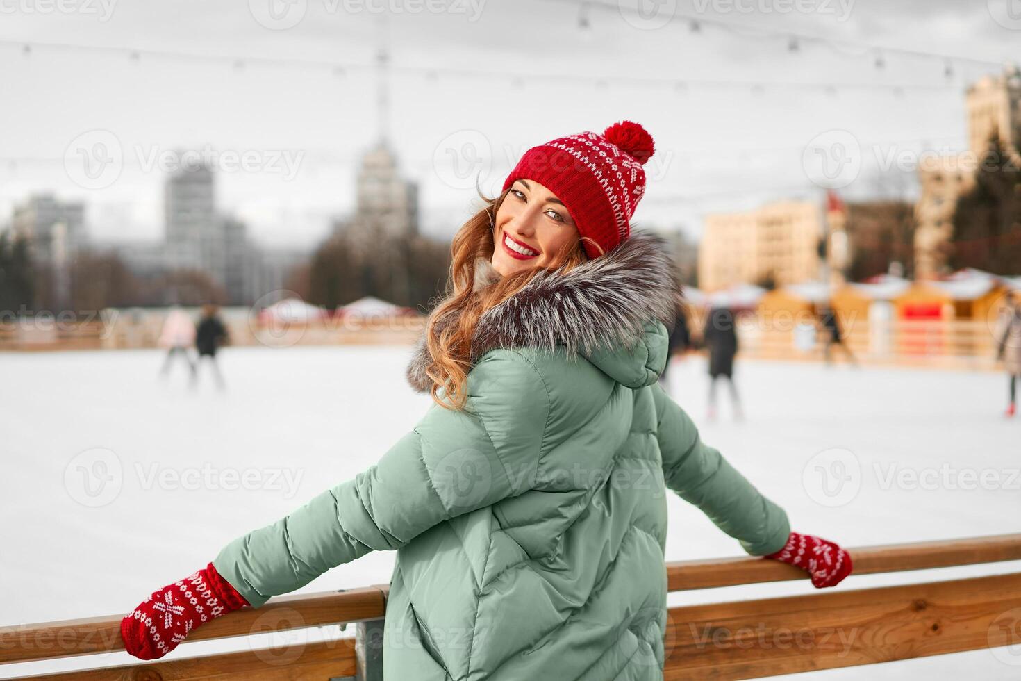 Beautiful lovely middle-aged girl with curly hair warm winter jackets stands ice rink background Town Square. photo