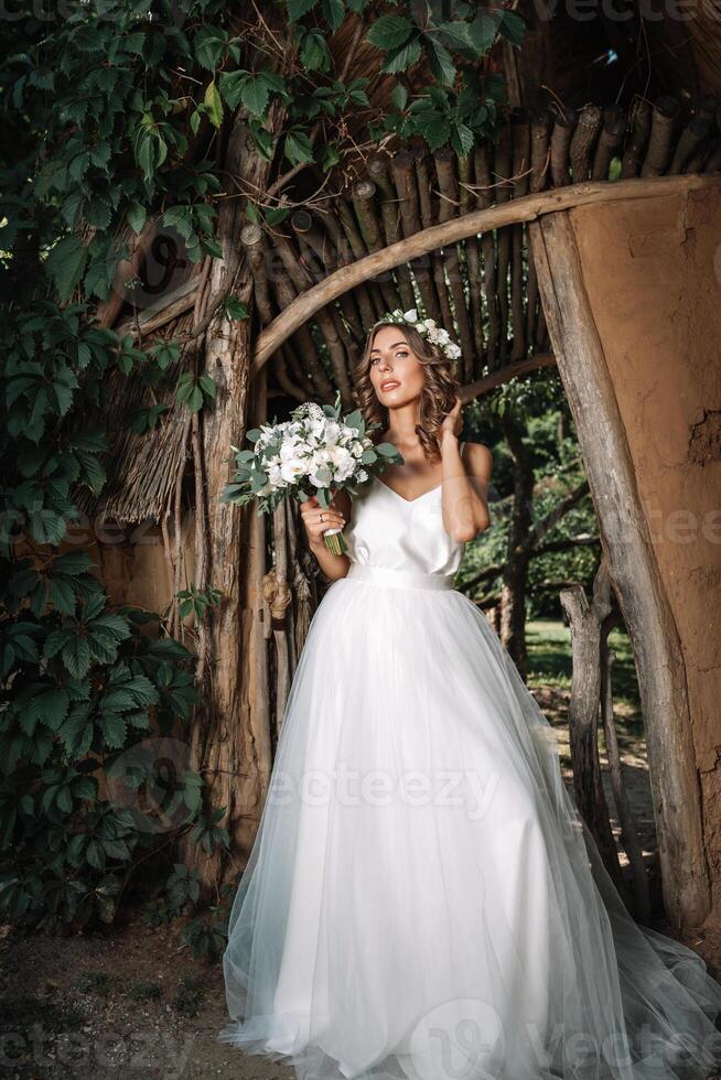 portrait of a beautiful young sexy girl bride with flowers in her hair look attractive in a white dress on a background of summer nature background posing and smiling photo