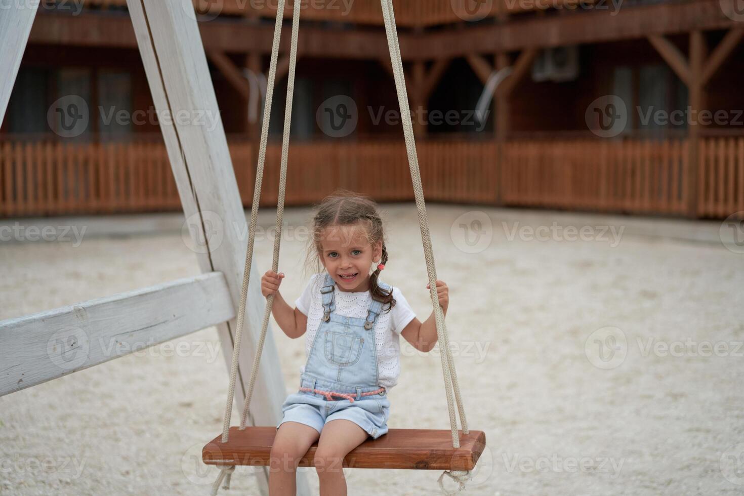 Playful kid swinging swing. Joyful little girl play having fun playground summertime photo