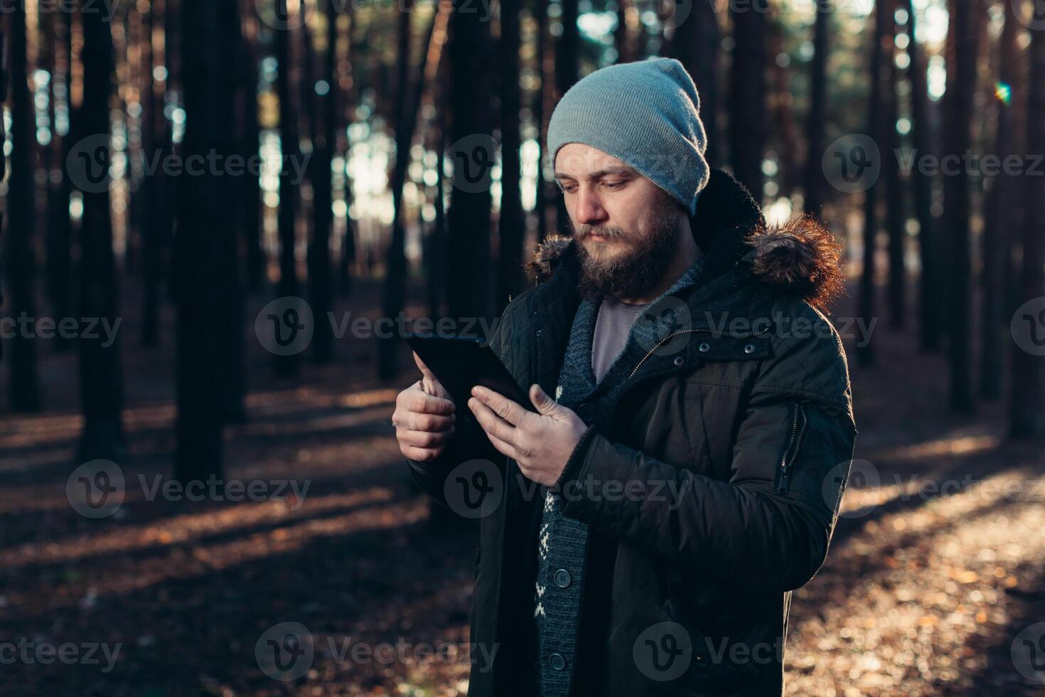 Close up portrait of adult male hiker using digital tab and looking for location during hike in nature. man on hike using digital tablet for navigation. photo