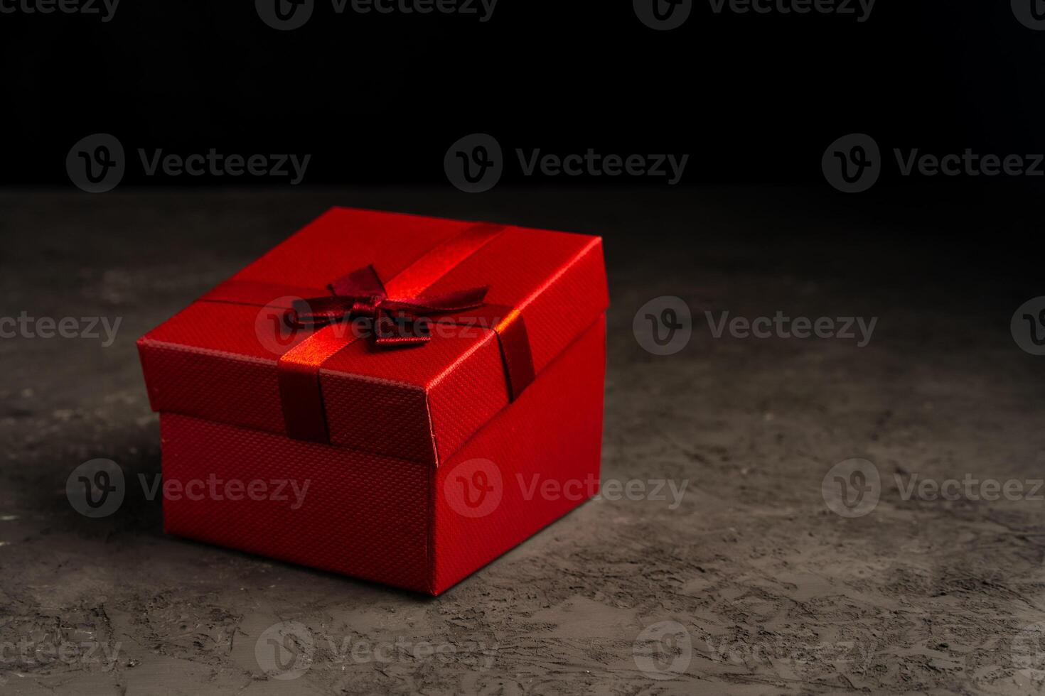 Red square holiday gift box against a dark background photo