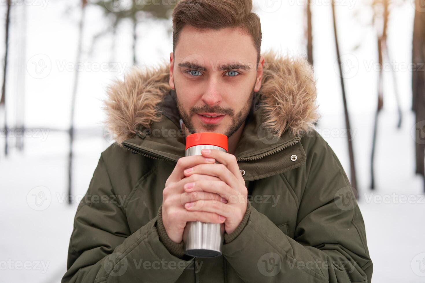 Attractive Caucasian man stands in winter forest near his car. photo