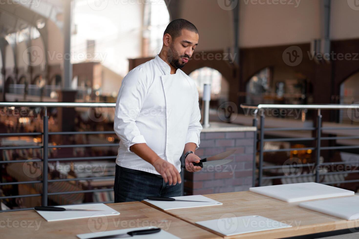 Handsome young chef African ethnicity lays knives on table in front of a culinary master class. photo