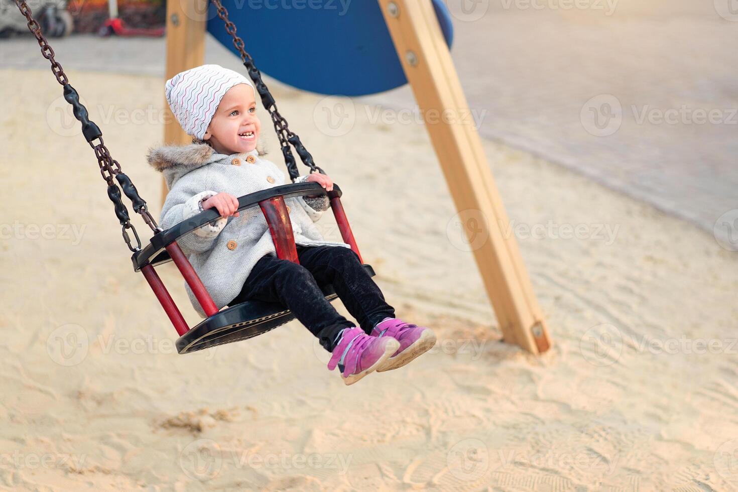 Happy child girl on swing in sunset fall. Little kid playing in the autumn on the nature park photo