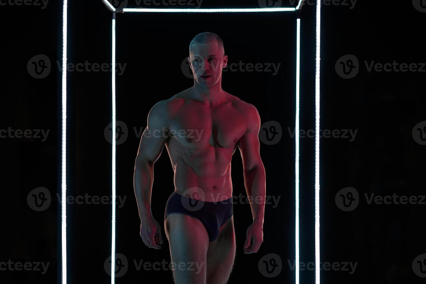 Active lifestyle concept. Professional bodybuilder showing perfect muscular body, lamps illumination on background photo