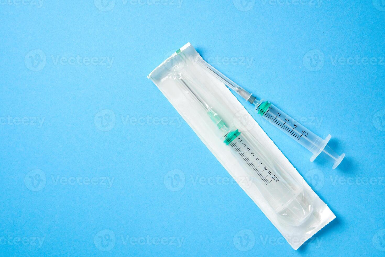 Two plastic disposable medical syringes open and package lie on blue background. photo