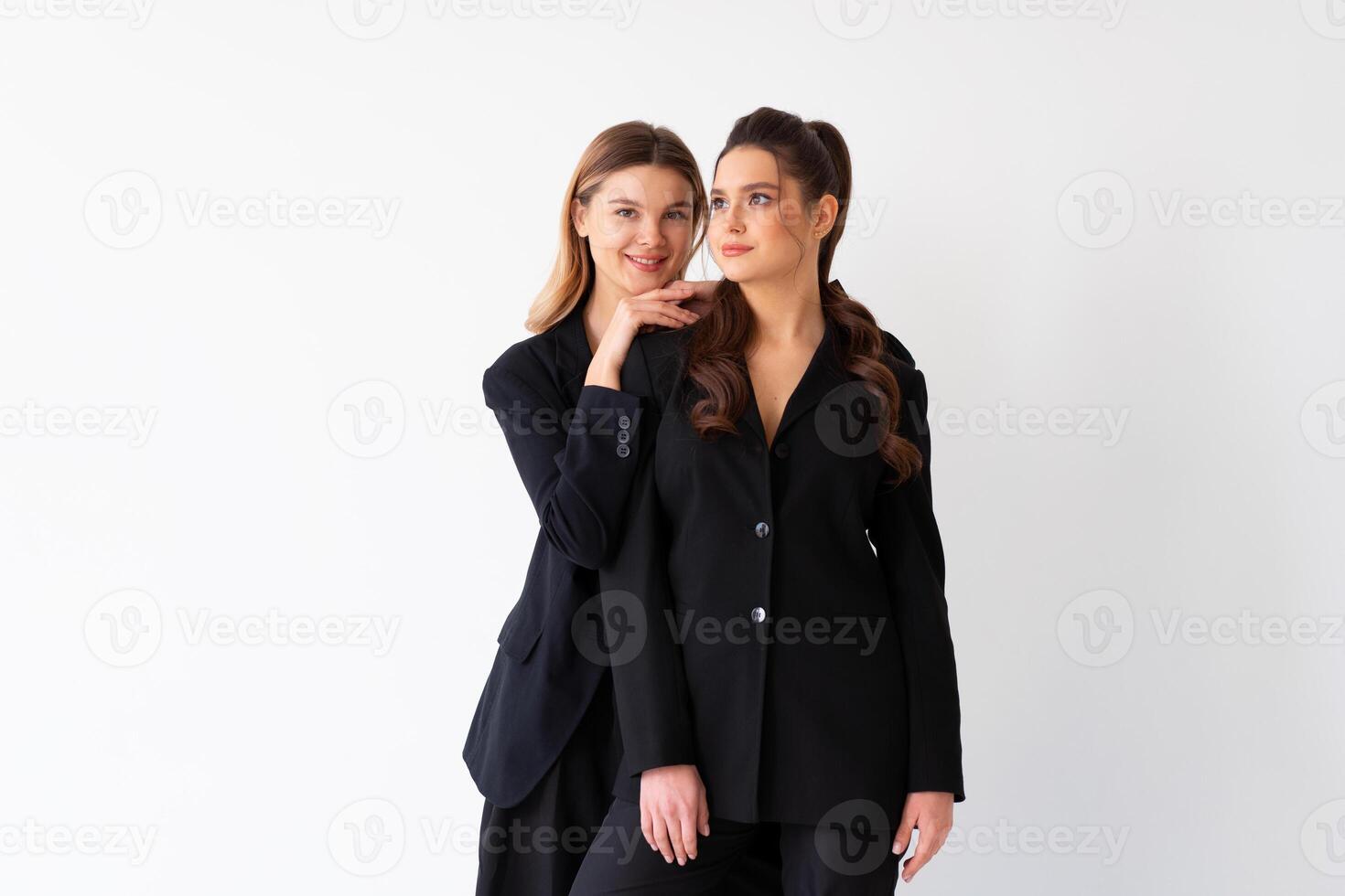 Concept of partnership in business. Two Young businesswoman dressed black formal suit standing studio isolated white background. photo