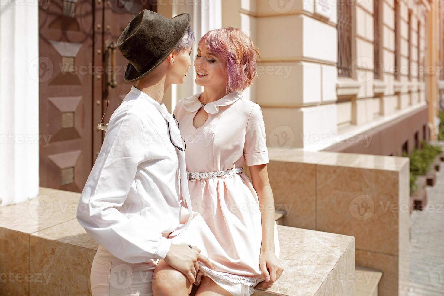 Two girls touching each other near the stairs of the building in the city photo