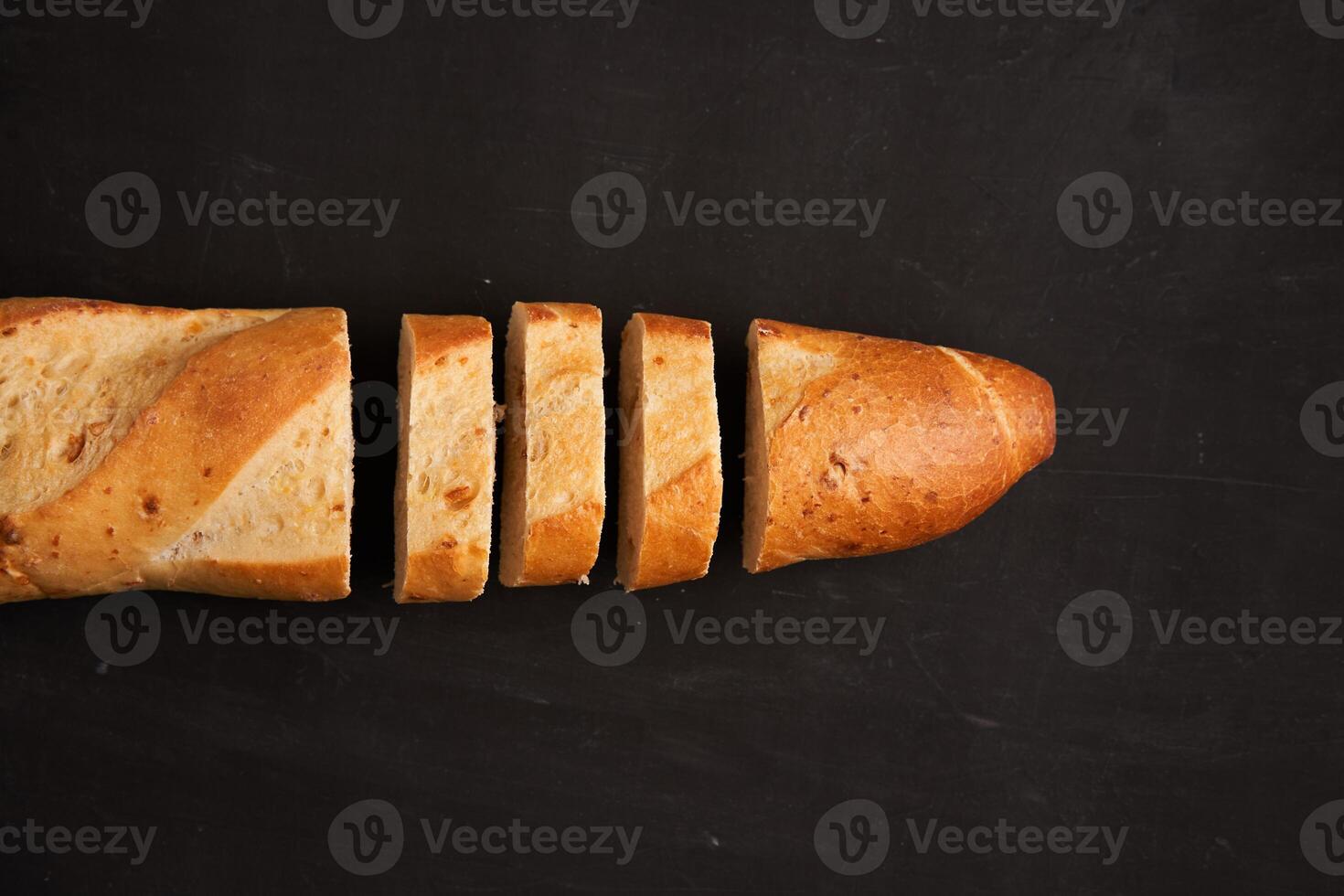 one sliced french baguettes lie on an old wooden table with free space for text photo