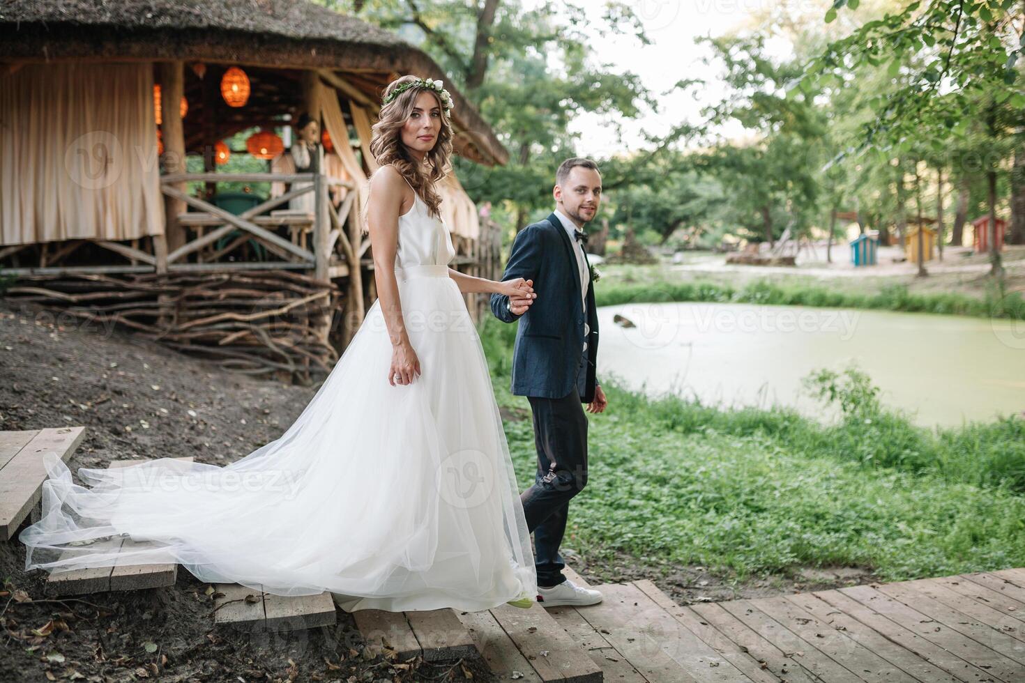 Bride and groom at wedding Day walking Outdoors on summer nature. Bridal couple, Happy Newlywed woman and man embracing in green park. Loving wedding couple outdoor. Bride and groom photo