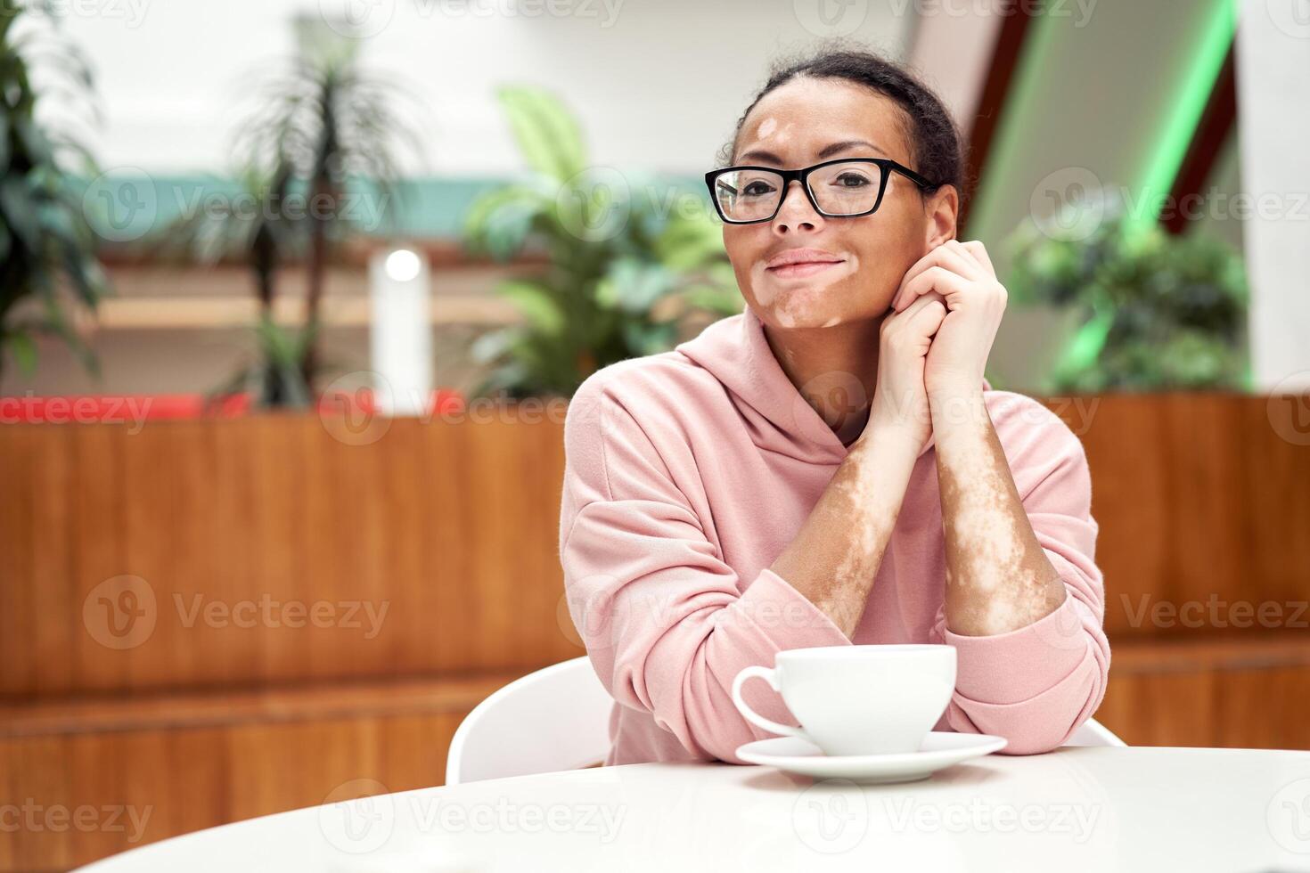 Black african american woman with vitiligo pigmentation skin problem indoor dressed pink hoodie photo