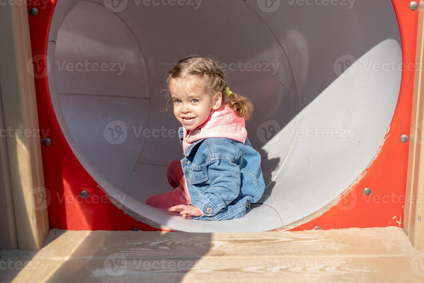 Cute little caucasian girl on the playground, happy child with pleasure spending time outdoors, happy carefree childhood photo