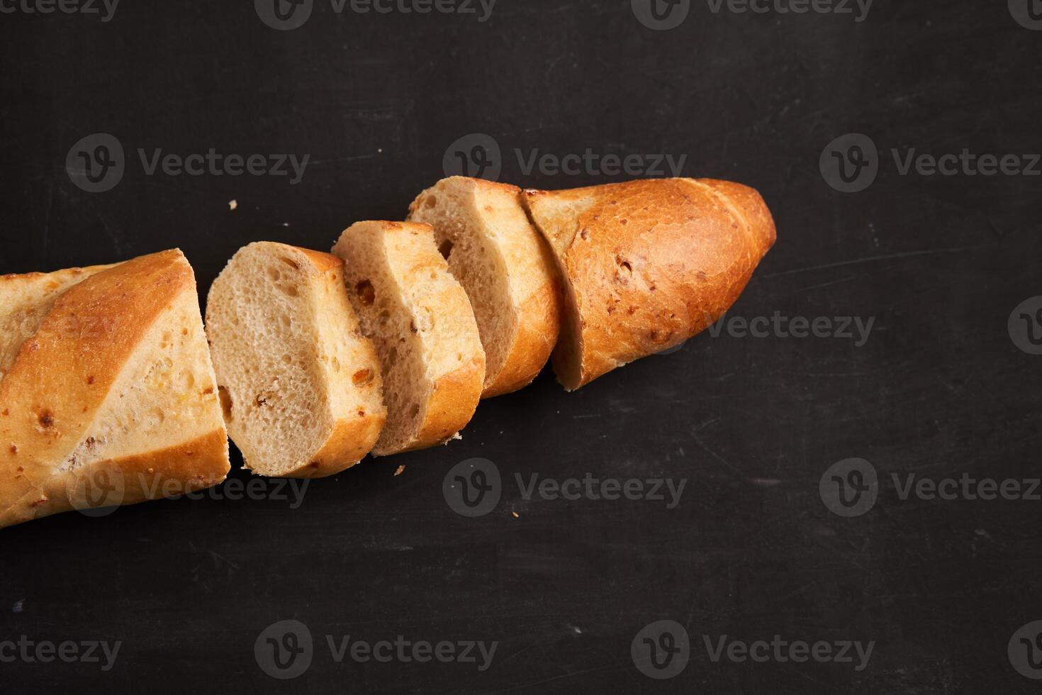 one sliced french baguettes lie on an old wooden table with free space for text photo