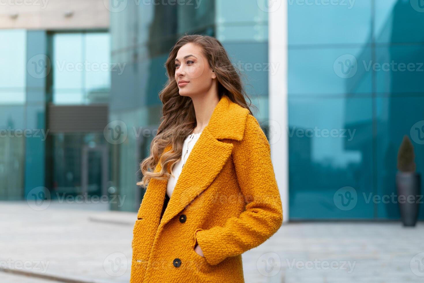 Business woman dressed yellow coat standing outdoors corporative building background photo