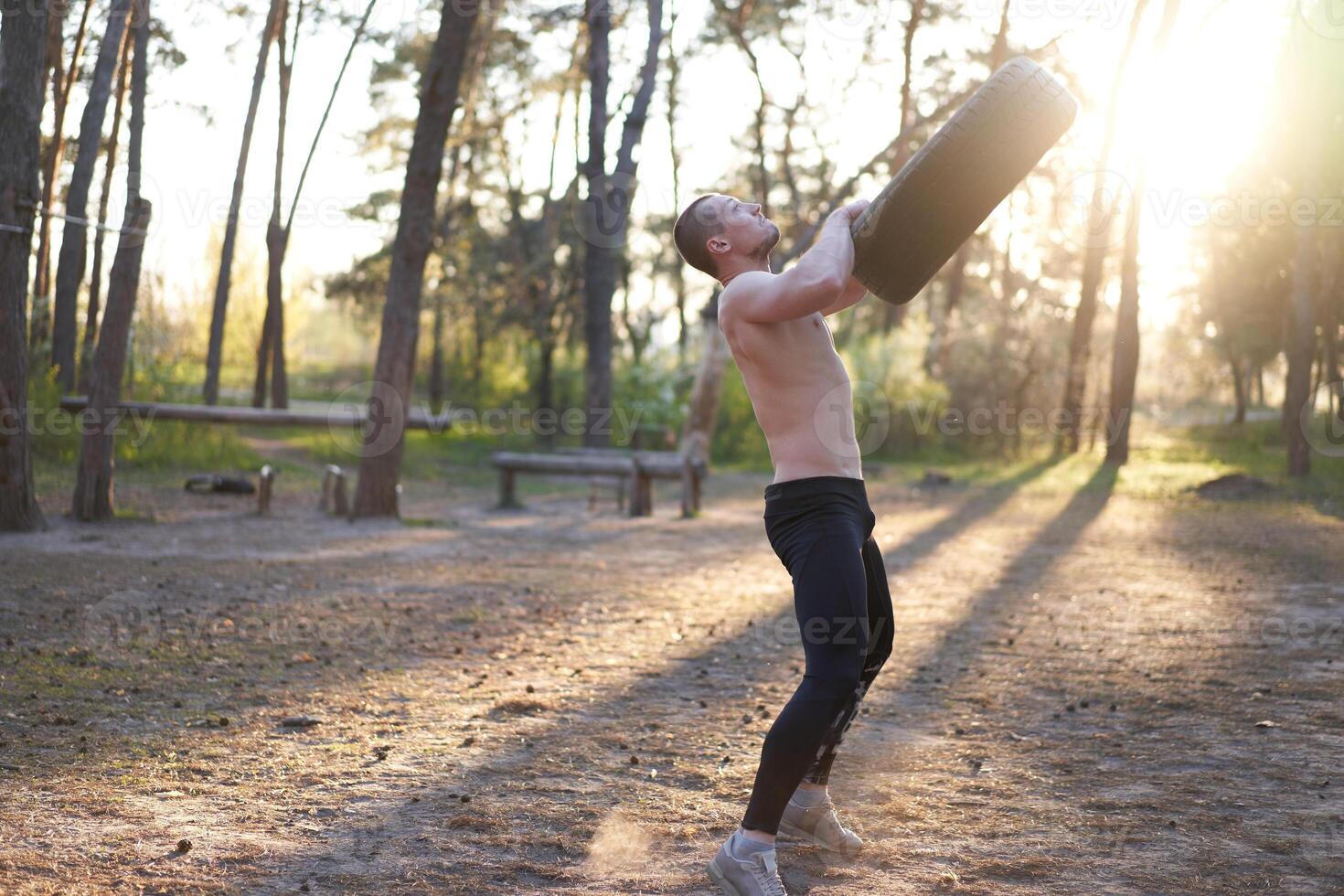 Strong man training workout lifting large tire outdoor DIY gym. photo