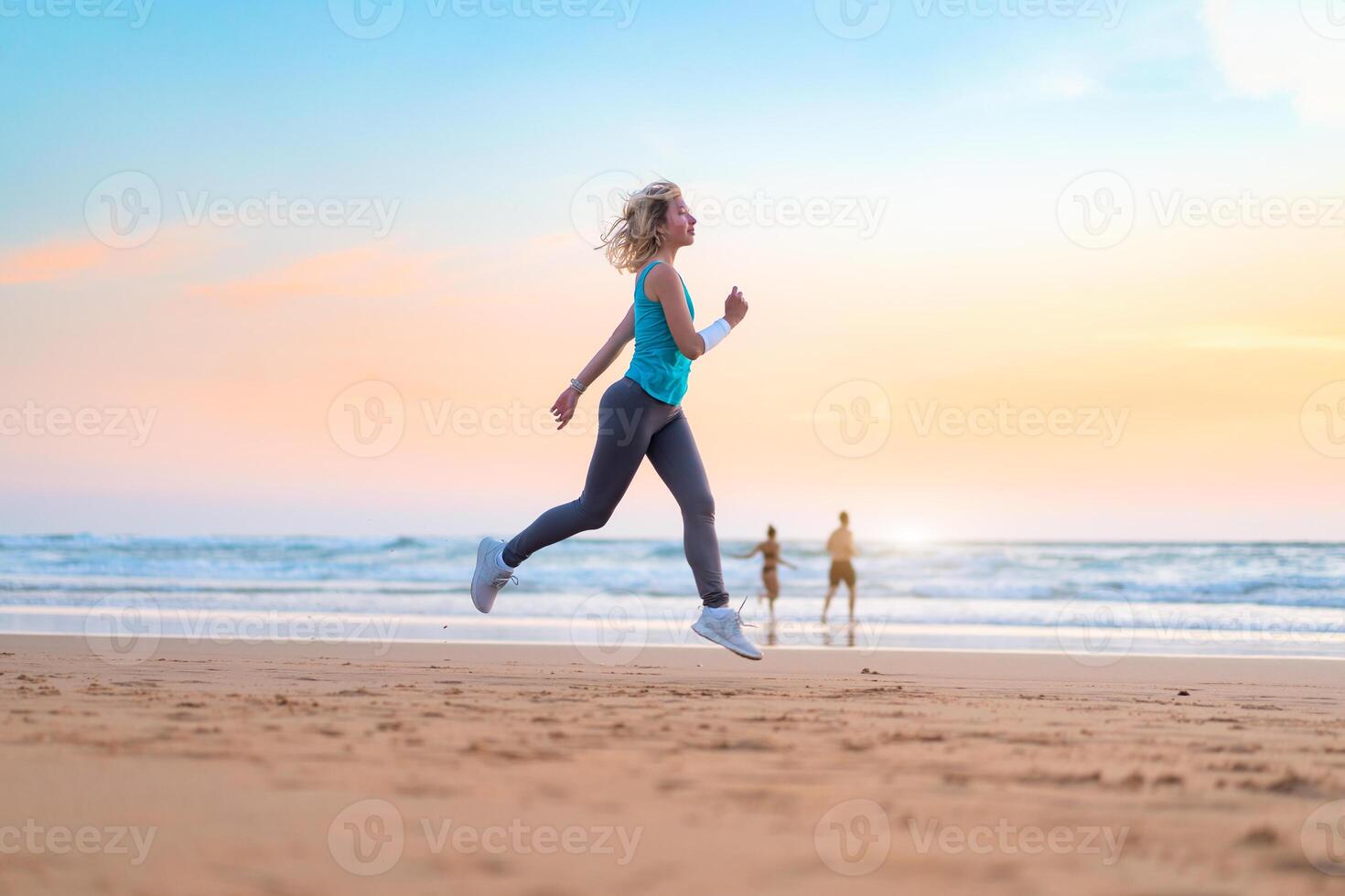 Active sporty woman run along ocean surf by water pool to keep fit and health. Sunset sand beach background with sun. Woman fitness, jogging workout and sport activity photo