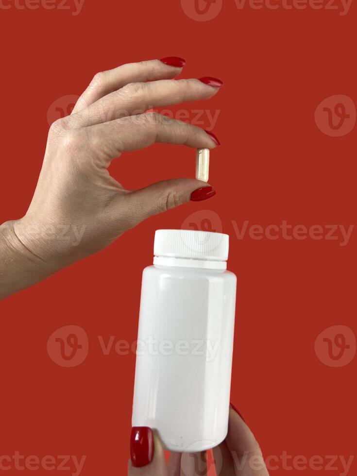 Woman holding pill and bottle on red background, closeup. Space for text photo