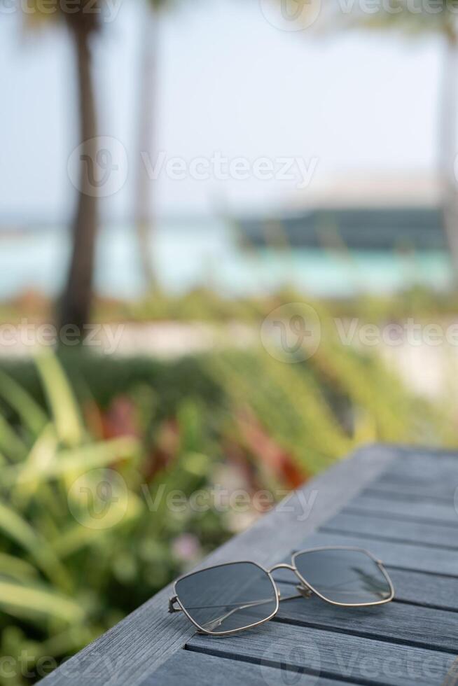 Sunglasses on wooden table on tropical beach background. photo