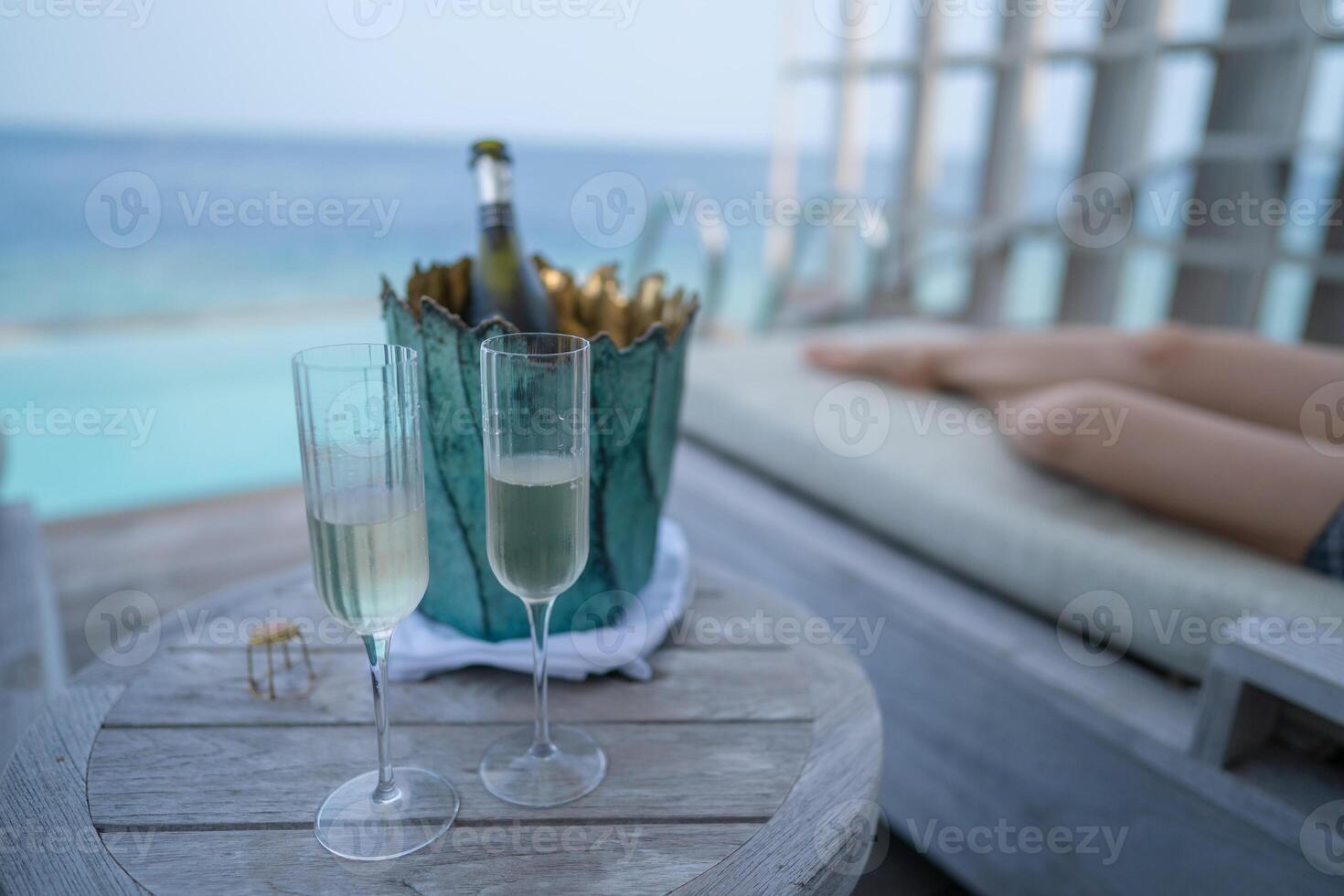 A champagne bottle on bucket filled with ice on with tropical ocean background. photo