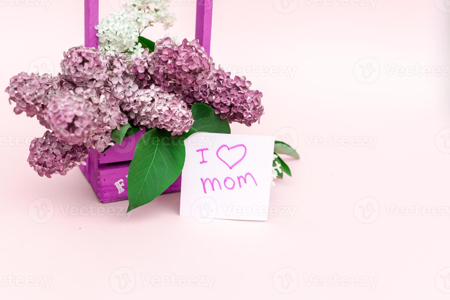 Beautiful bouquet of purple lilac and card on purple paper background photo