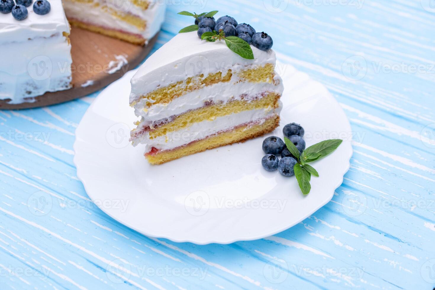 Appetizing cheesecake cake biscuit pillow decorated white cream blueberries and mint stands on wooden blue rustic table photo