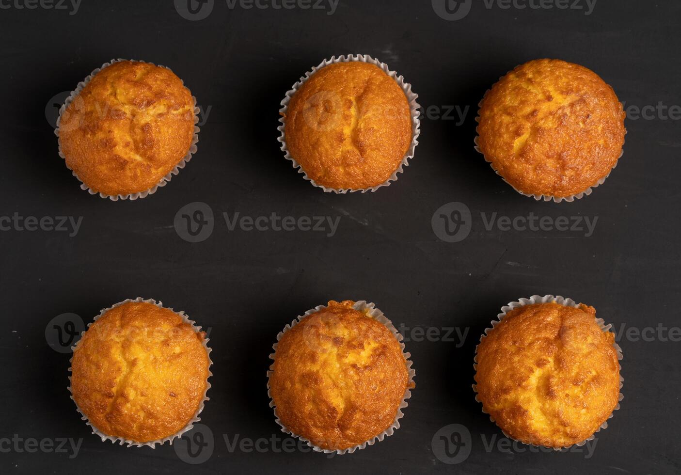 Appetizing muffins stand on a table top view. Traditional pastries on a dark background minimalism. photo