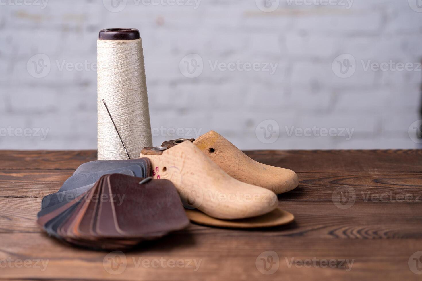 Leather samples for shoes and wooden shoe last on dark wooden table. photo