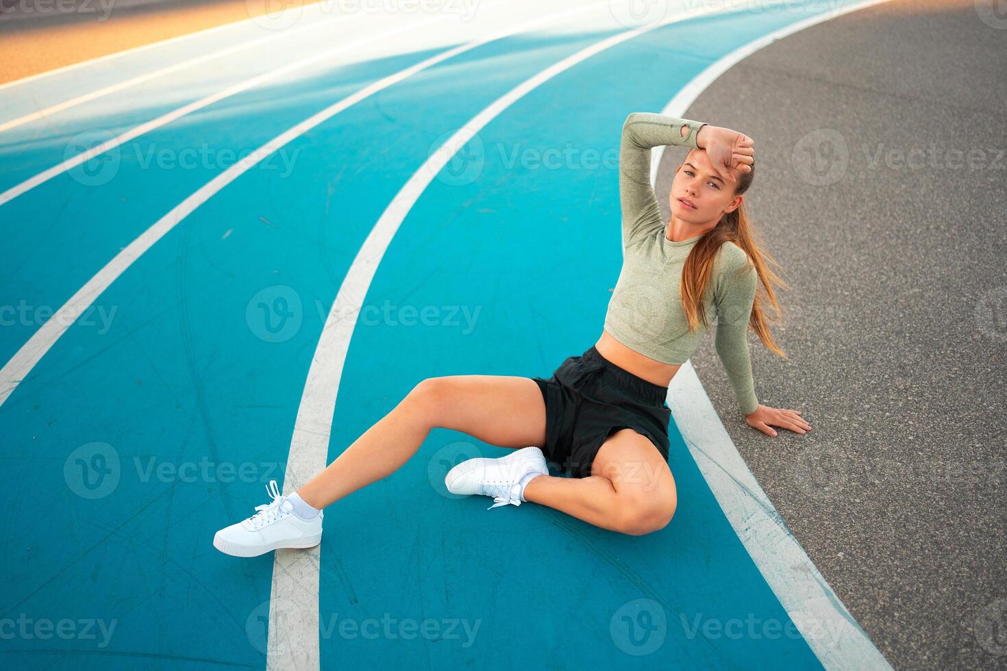 Full length upset sporty woman sitting on running track photo