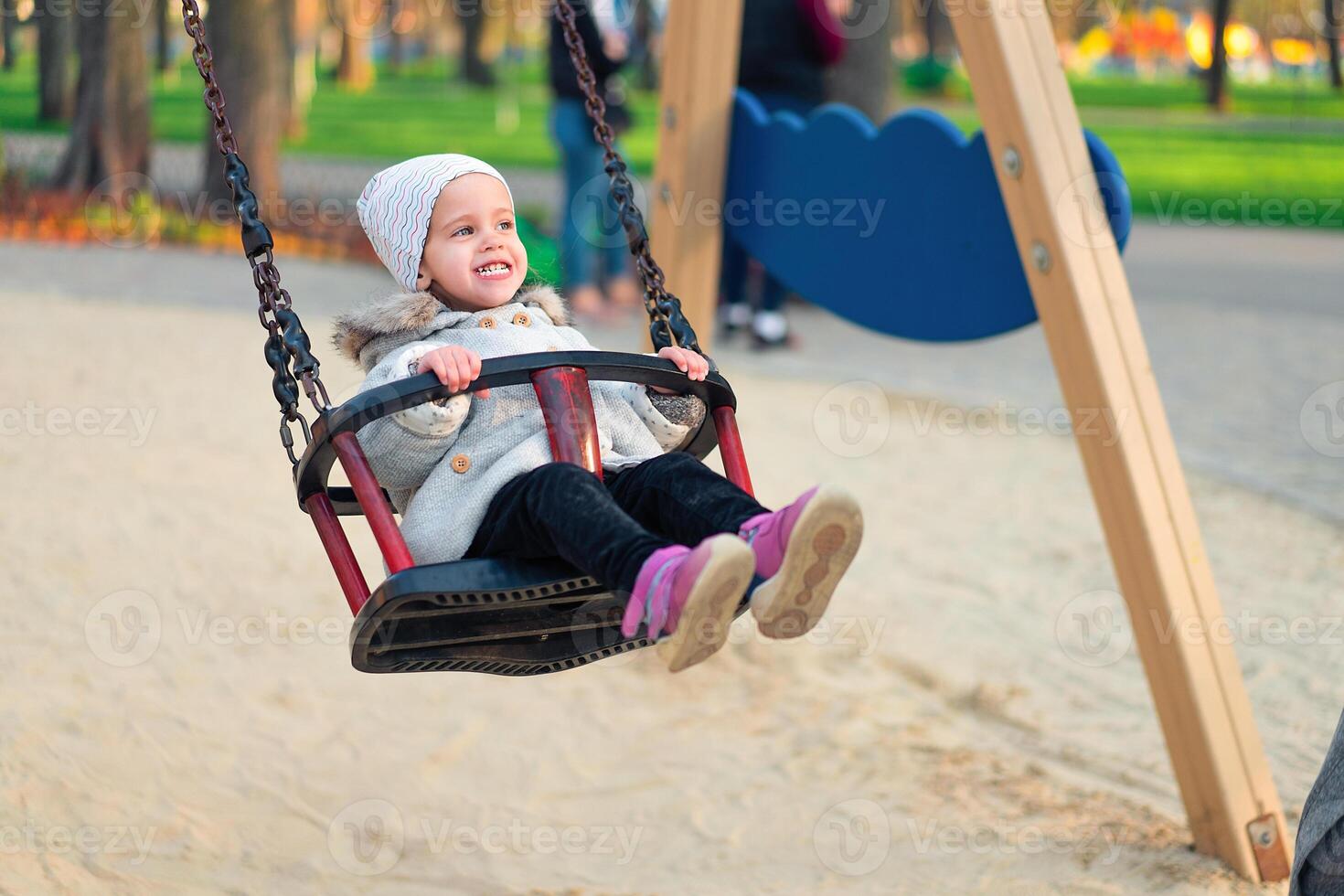 Happy child girl on swing in sunset fall. Little kid playing in the autumn on the nature park photo