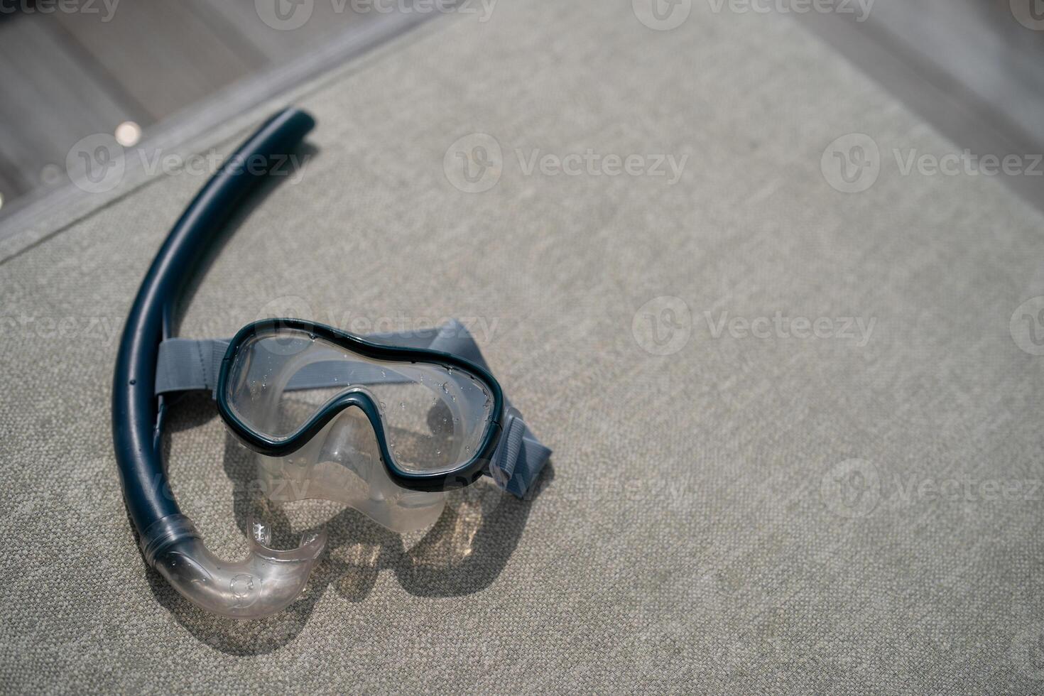 Snorkel and swimming mask lie on a gray pad background. photo