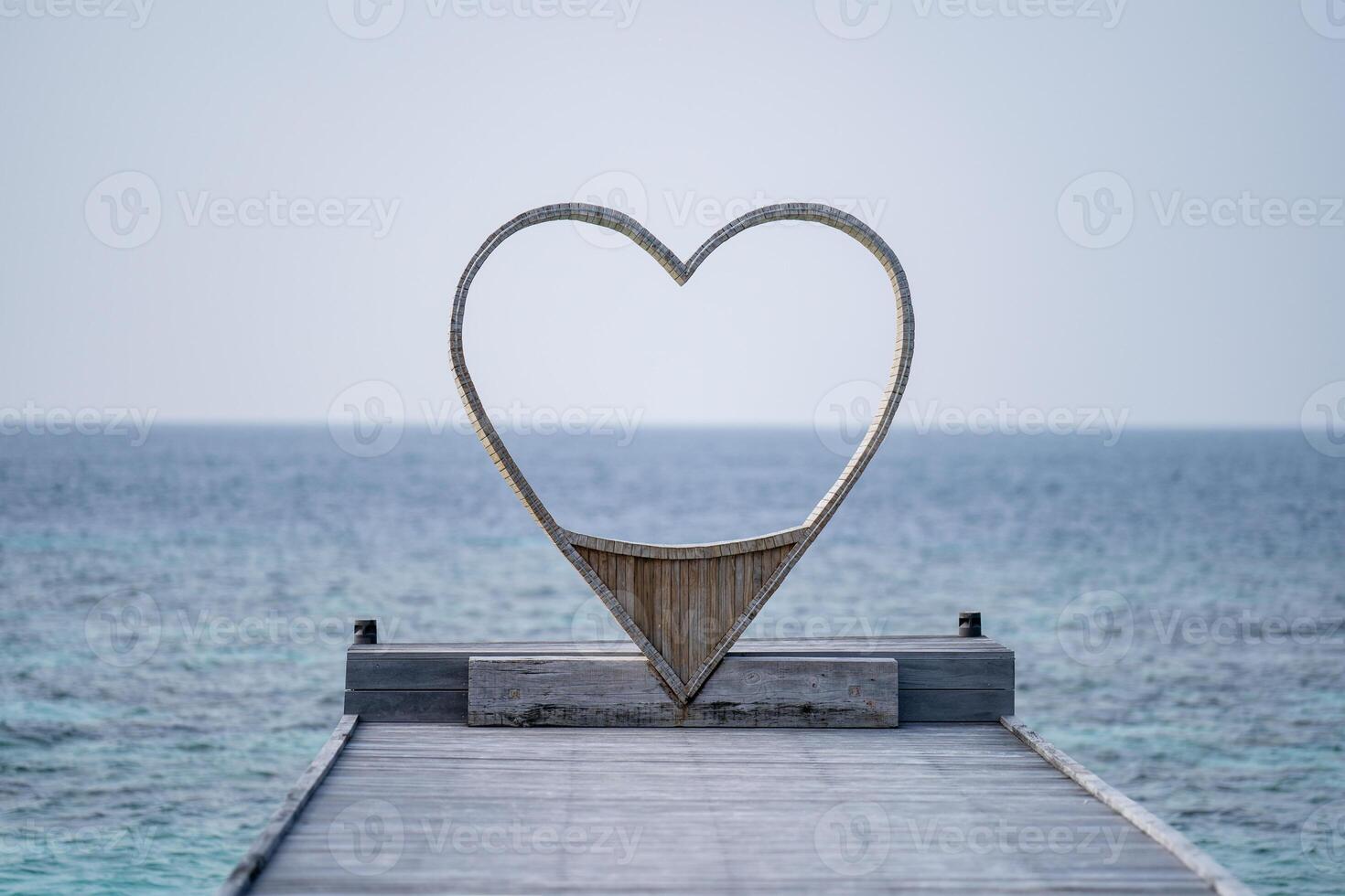 Wooden heart shaped chair looking through the sea  for couple, ocean background. photo
