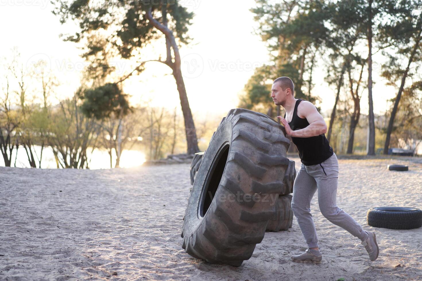 Strong man training workout lifting large tire outdoor DIY gym. photo