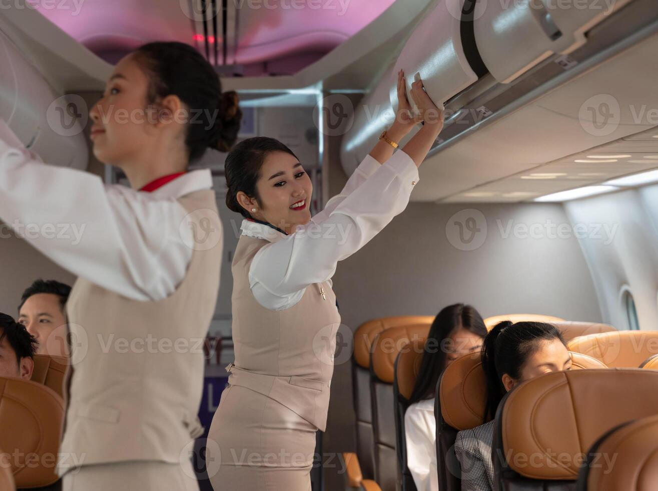 Airplane flight attendant closing overhead luggage cabin in airplane photo