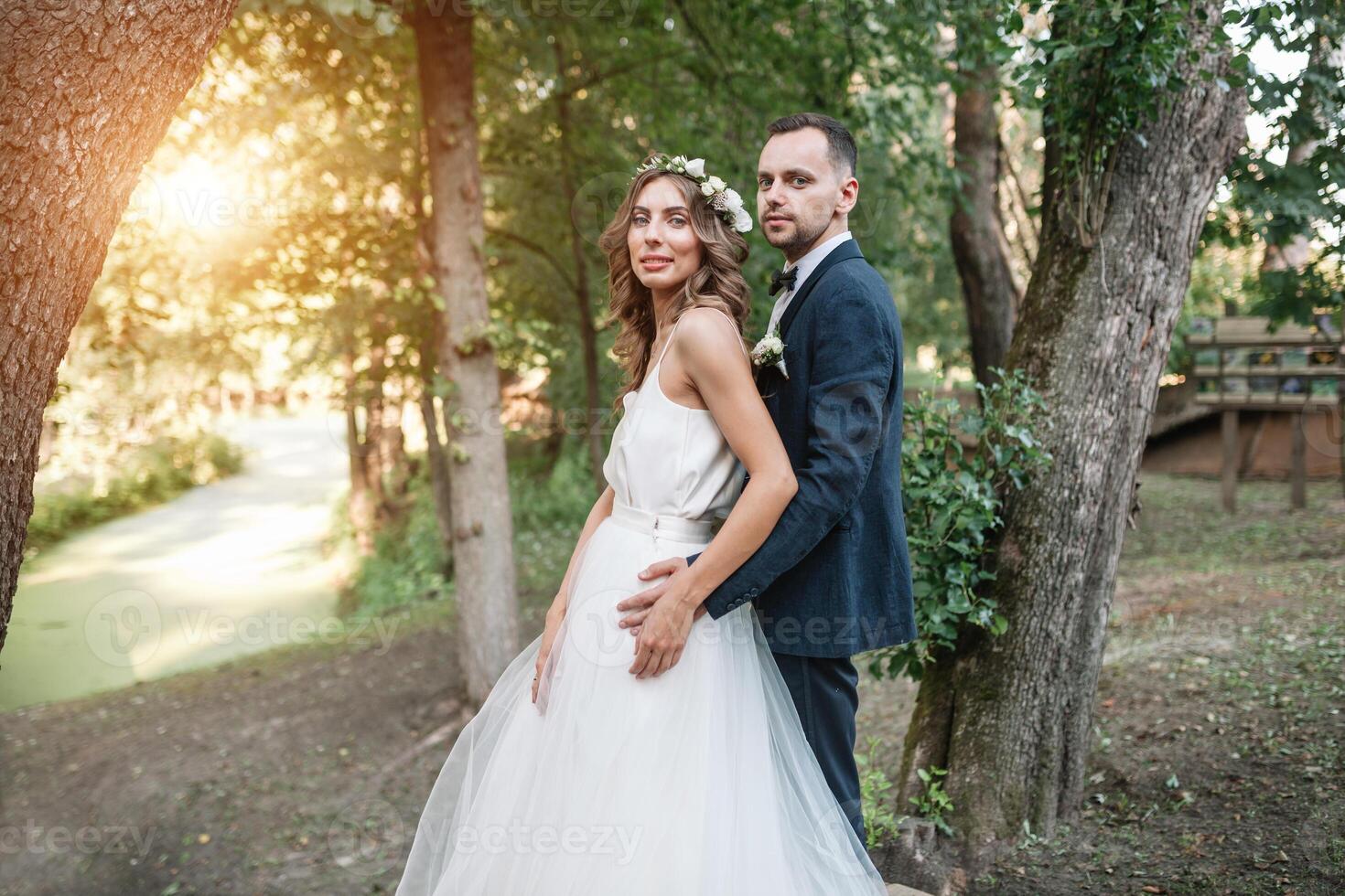 novia y novio a Boda día caminando al aire libre en verano naturaleza. nupcial pareja, contento recién casado mujer y hombre abrazando en verde parque. amoroso Boda Pareja exterior. novia y novio foto