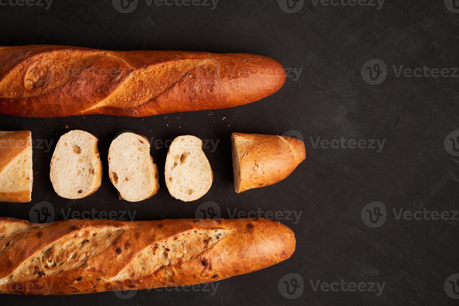 Three crispy french baguettes lie on an old wooden table with free space for text photo