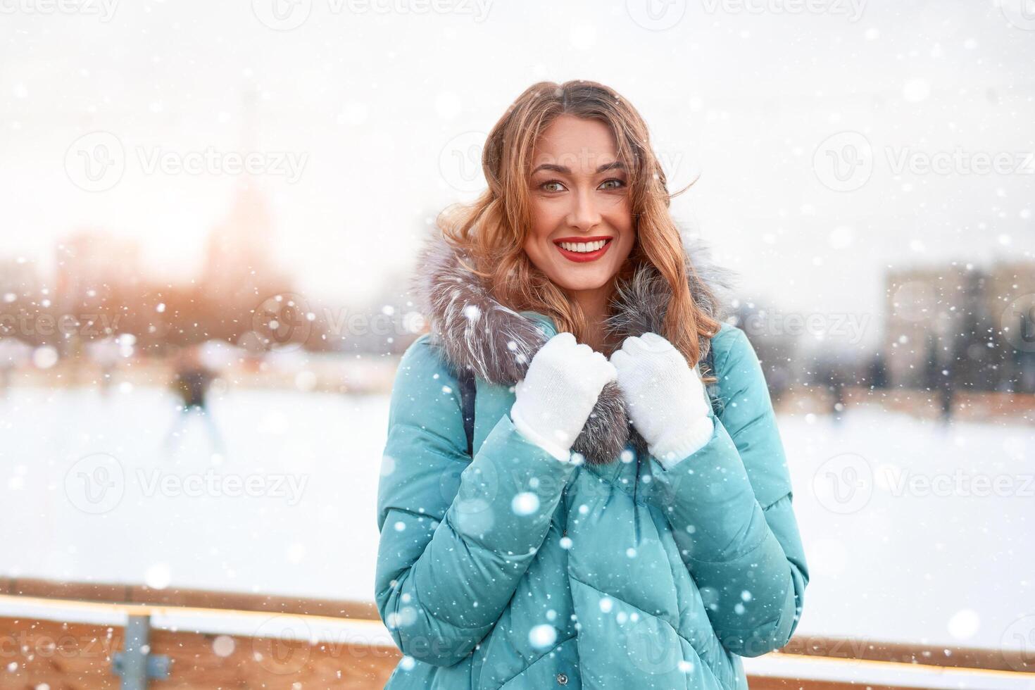 Beautiful lovely middle-aged girl with curly hair warm winter jackets stands ice rink background Town Square. photo