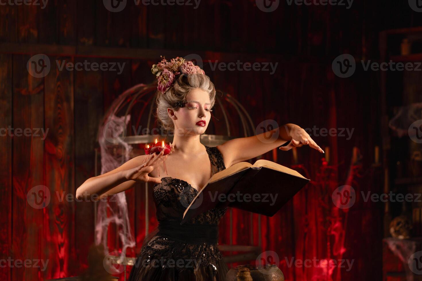 Charming woman witch flowers in hair vintage black dress with book of spell in the old castle. Halloween. Celebration. photo