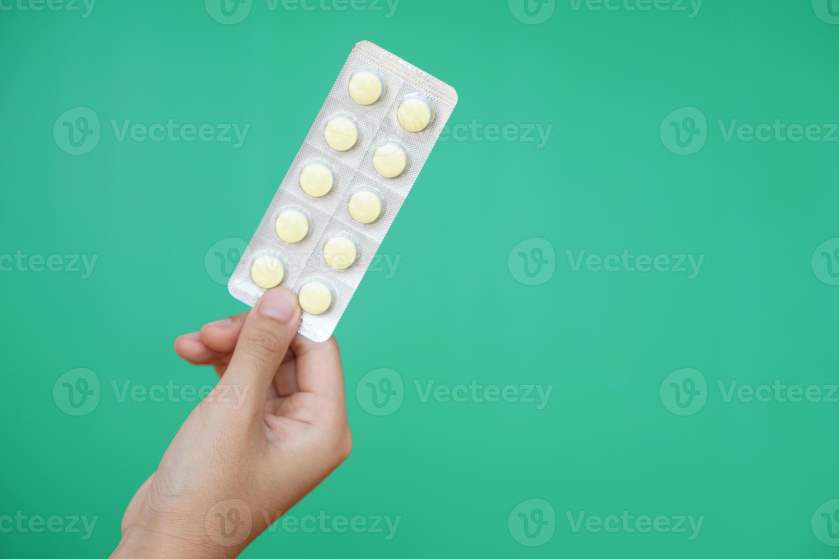 Close up hand hold blister pack of medicine pills. Green background