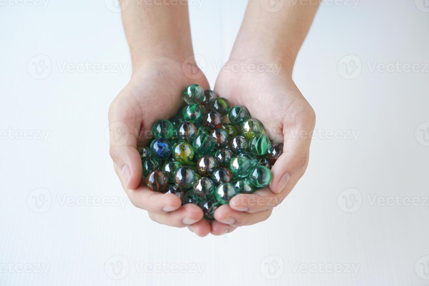 Close up hands holds marbles balls, small spherical object often made from glass, clay, steel, plastic, or agate. Concept. object use as toy for playing games or use for DIY craft decoration. photo