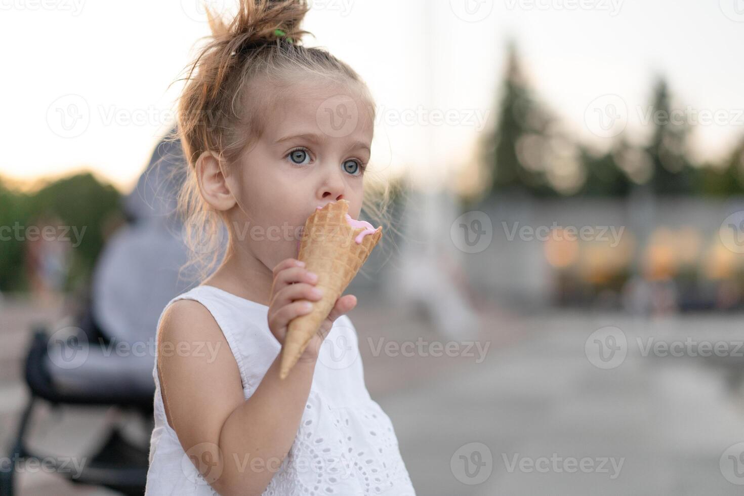 Little caucasian girl 3 years old eats ice cream closeup portrait photo
