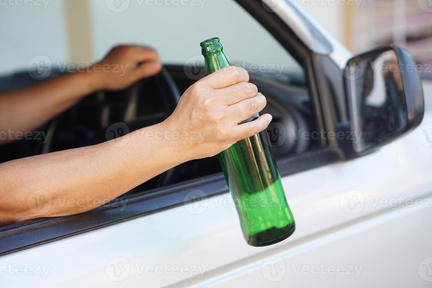 Close up a driver holds bottle of beer in car. Concept , Campaign for don't drive, don't drink alcohol that can cause car accident and illegal. Dangerous driving when drunk. photo