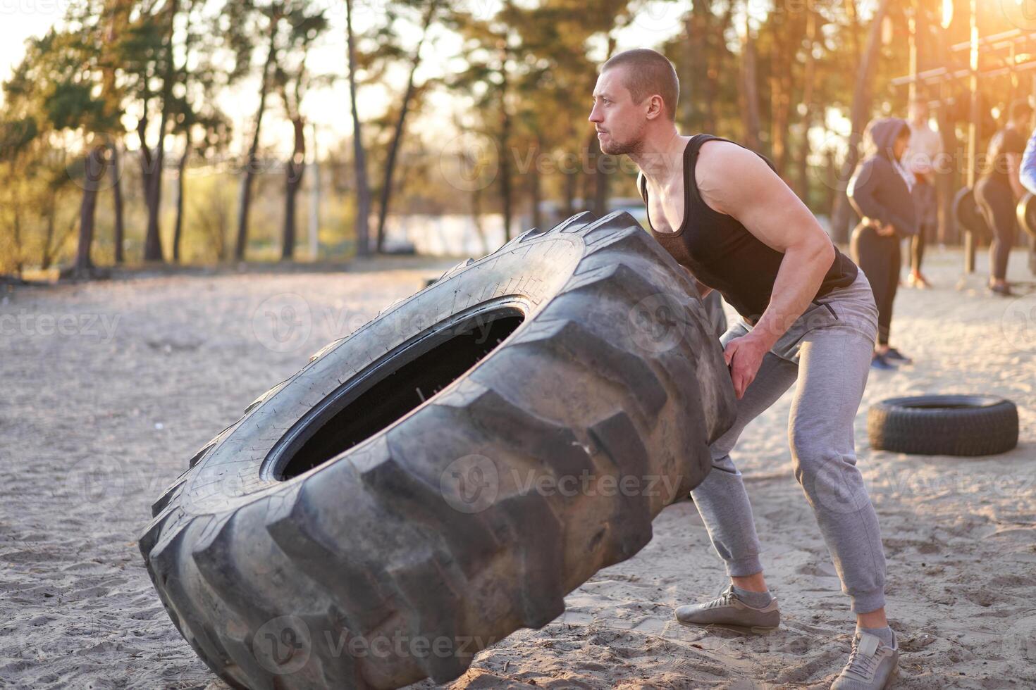 Strong man training workout lifting large tire outdoor DIY gym. photo